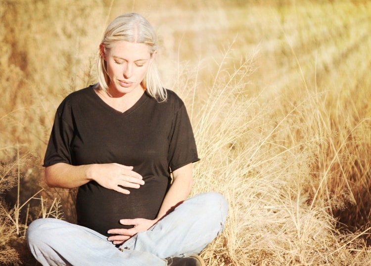 trimestrul 2 de sarcina femeie gravida blonda afara in lotus soare