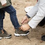 Close up of mother helping her child tying the shoes