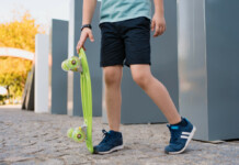 close-up-legs-blue-sneakers-with-green-skateboard-active-urban-lifestyle-youth-training-hobby-activity-active-outdoor-sport-kids-child-skateboarding-
